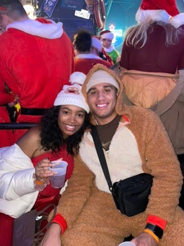 Cayla and Shaddy smile together in festive winter outfits.