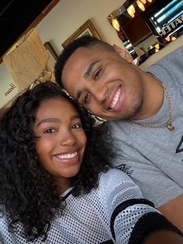 Cayla and Shaddy smiling together in a close-up café selfie.